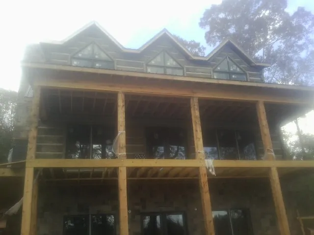Dormers and porch framing on a large log home under construction — Roof Coating work by our crew in Owens Cross Roads