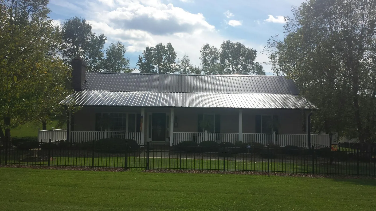 Gray metal roof on a brick ranch with a full width front porch in Owens Cross Roads